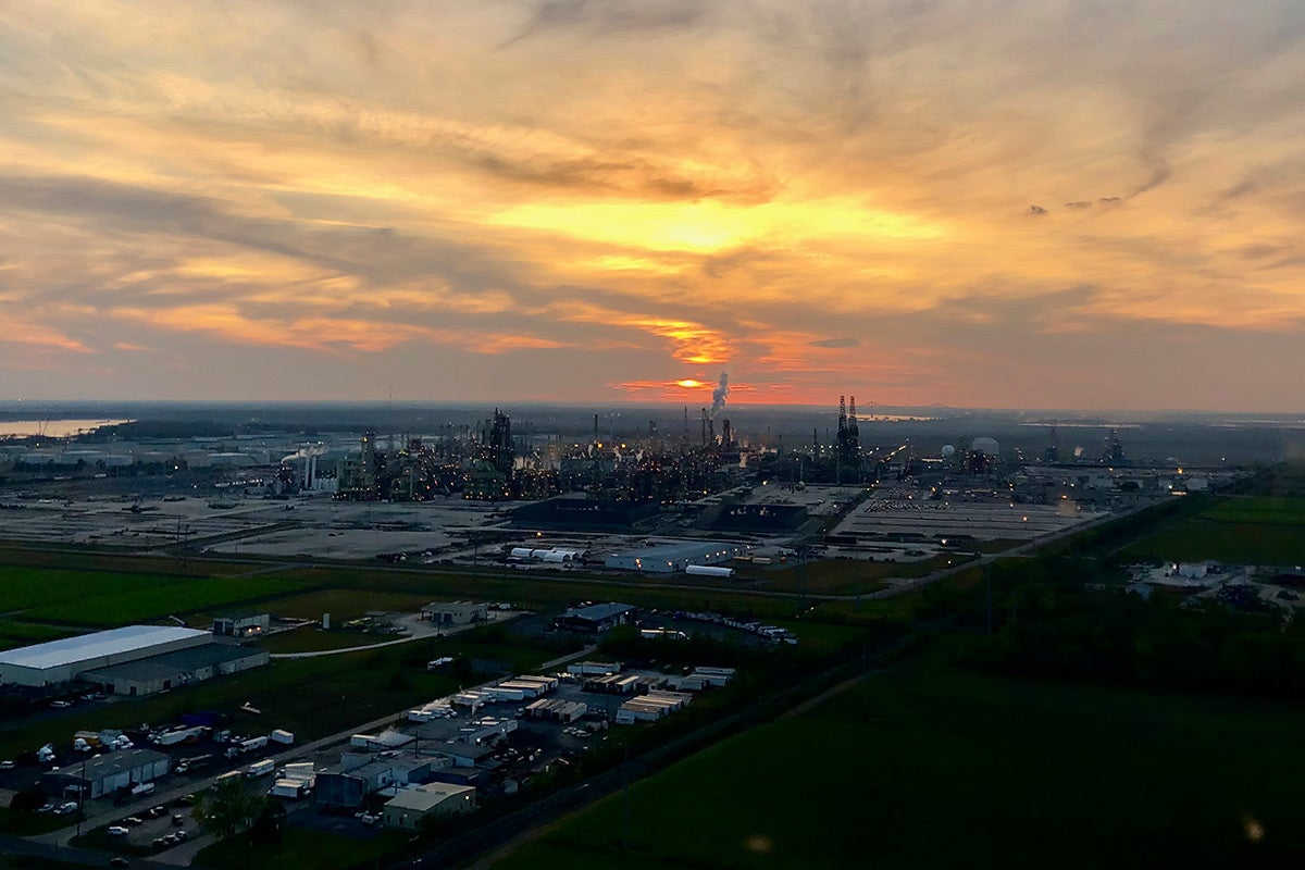 An aerial view of Reserve, Louisiana, at sunset. A large petroleum factory is visible.